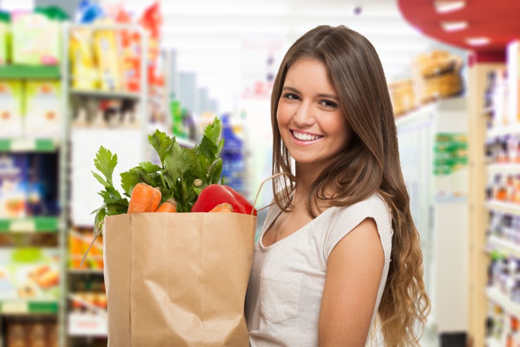 Woman holding a paper bag with veggies